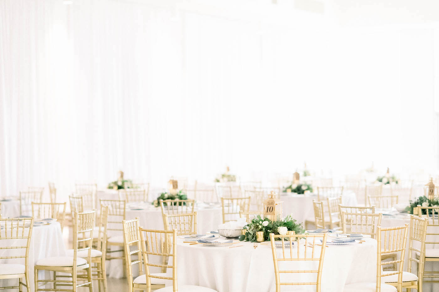 Tampa Wedding Venue the Tampa Garden Club Indoor Reception | Wedding Reception Tables with White Linens and Gold Chiavari Chairs and Low Greenery and Lantern Centerpieces | Gabro Event Services