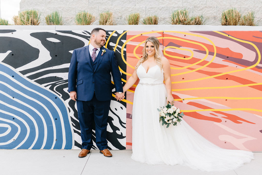 Florida Bride and Groom Fun Wedding Portrait with Art Mural Wall, Holding White, Ivory and Blush Pink Floral Bridal Bouquet