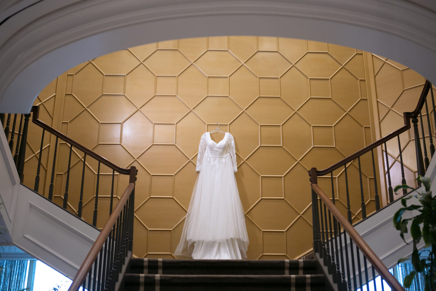 Romantic Long Sleeve Lace and Tulle Wedding Dress Hanging on Unique Wall at Wedding Venue Staircase The Tampa Club | Wedding Photographer Carrie Wildes Photography