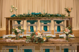 Rustic Wedding Reception Decor, Long Wooden Tables with Blue Teal Chair Sashes, Pink Orange and Mauve Roses, White Florals and Greenery Bouquets, Eucalyptus Table Runner | Wedding Photographer Carrie Wildes Photography | Wedding Linens Gabro Event Services