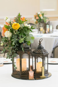 Rustic Wedding Reception Decor, Circular Mirror Tray with Black Lanterns and Candles, Yellow, Orange, and White Roses with Greenery Florals Centerpiece | Wedding Photographer Carrie Wildes Photography
