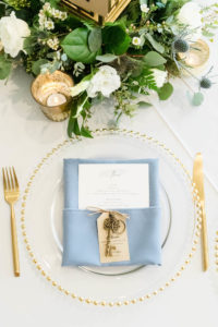Wedding Place Setting with Gold Flatware and Gold Beaded Edge Glass Charger Plate and Dusty Blue Napkin with Menu and Brass Key Favor | Gabro Event Services | Lynn's Catering of Tampa