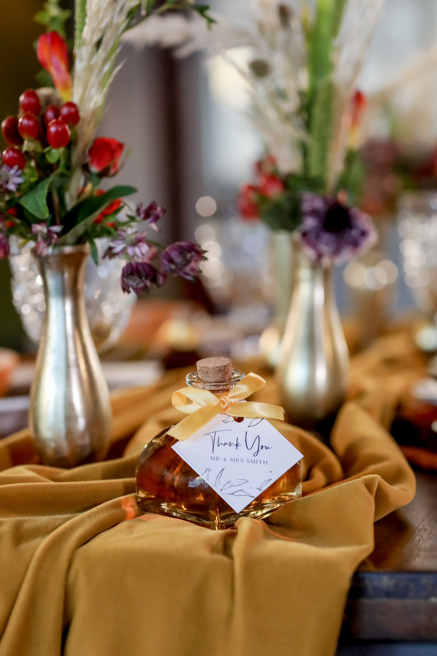 Bohemian Inspired Florida Wedding Reception and Decor, Autumn Table setting, Mustard Yellow Flowy Table Runner, Low Floral Centerpieces in Pewter Vases, with Deep Red, Purple, and Eggplant Flowers, Greenery with Pampas Grass, Custom Honey Thank You Gift, Crystal Glasses | Downtown St. Petersburg Wedding Planner Blue Skies Weddings and Events | Florida Wedding Photographer Lifelong Photography Studio