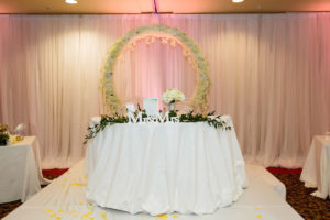 Classic Romantic Wedding Reception Decor, Sweetheart Table with White Linens and Backdrop, Pink Uplighting, Circular White and Ivory Floral Wreath Arch, Greenery Garland, Mr and Mrs Signs | Tampa Bay Wedding Planner Special Moments Event Planning | Clearwater Beach Wedding Venue Duvall Ballroom Center | Wedding Rentals Gabro Event Services