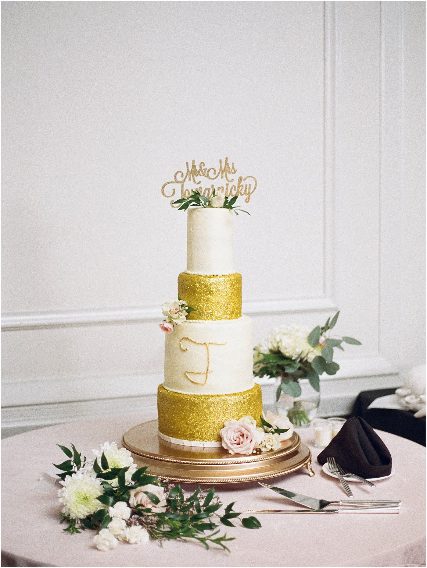 Four Tier Wedding Cake with Gold Glitter and Fresh Floral Accents topped with Gold Die Cut Name Topper