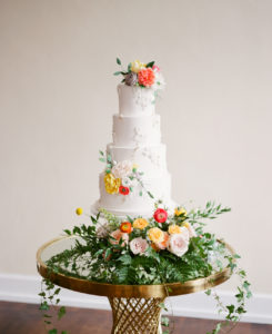 Elegant, Springtime Inspired Florida Wedding Cake, Four Tier Circular White Buttercream Cake with Floral Accents, Peach, Yellow, Orange, Pink and Red Flowers, And Greenery | Tampa Bay Wedding Kelly Kennedy Weddings and Events