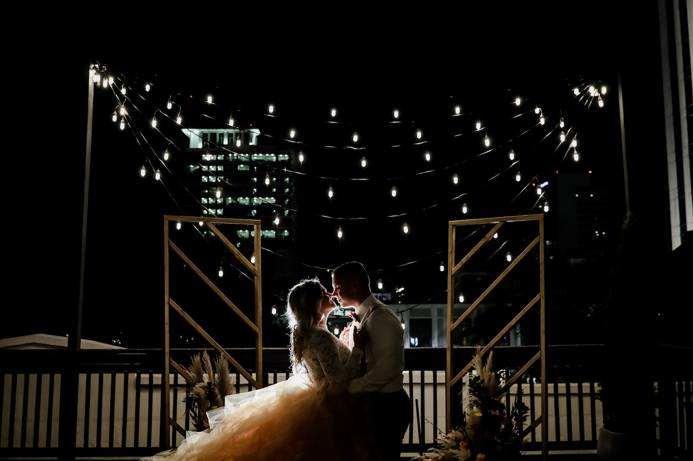 Boho Inspired Bride and Groom Silhouette Portrait on Wedding Venue Rooftop with City Backdrop, Hanging String Lights, Geometrical Stands | Tampa Bay Wedding Planner Blue Skies Weddings and Events | Downtown St. Petersburg Wedding Photographer Lifelong Photography Studio | Unique Florida Wedding Venue Station House in DTSP