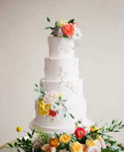 Elegant, Springtime Inspired Florida Wedding Cake, Four Tier Circular White Buttercream Cake with Floral Accents, Peach, Yellow, Orange, Pink and Red Flowers, And Greenery | Tampa Bay Wedding Kelly Kennedy Weddings and Events