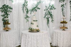Elegant Wedding Cake and Dessert Table at Wedding Reception, Four Tier White Buttercream Wedding Cake with Textured Frosting, Greenery Floral Accents, Gold Cake Stand, Last Name Initial Topper, Lace Linen Cake Tablecloth | Florida Wedding Planner Parties A'La Carte | Downtown St. Petersburg Wedding Florist Bruce Wayne Florals