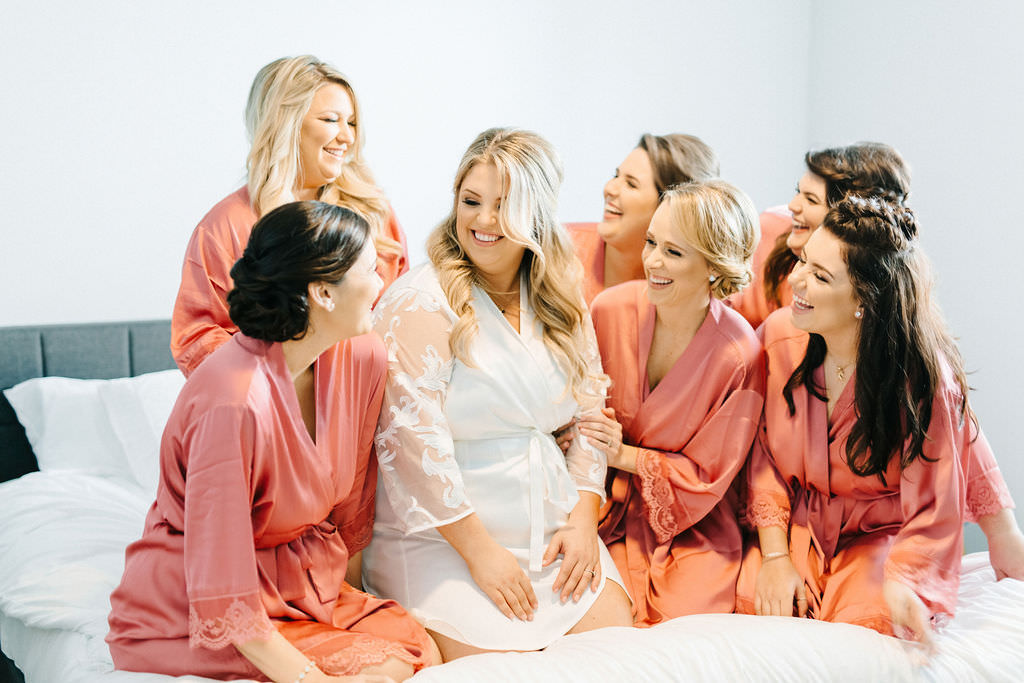 Florida Bride and Bridesmaids Getting Wedding Ready Photo on Bed in Matching Rose Pink Silk Robes