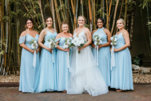Tampa Bay Bride and Bridesmaids in Enchanting Bamboo Courtyard, Bridal Party Wearing Long Mix and Match Sky Blue Azazie Dresses, Holding White Rose Bouquets with Greenery | Florida Wedding Photographer Bonnie Newman Creative | St. Petersburg Wedding Venue NOVA 535 | Wedding Hair and Makeup Artist Femme Akoi Beauty Studio