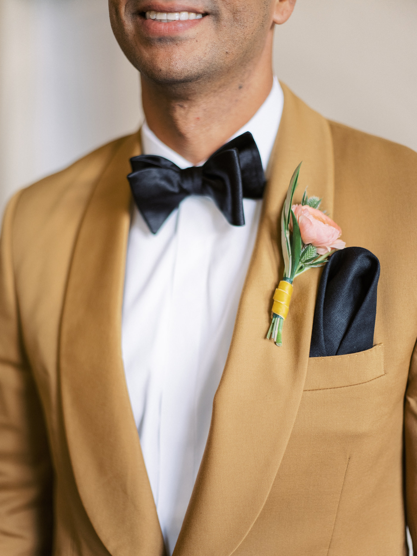 Elegant Florida Groom Wearing Yellow Mustard Suit Jacket from The Black Tux, Light Pink Floral Boutonnière with Yellow Ribbon, Black Silk Bow Tie and Pocket Square