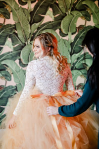 Unique Vintage Bohemian Inspired Florida Bride Wearing White Lace Long Sleeve Top, Oversized Full Tulle Skirt with Long Train in Blush Peach Orange and Silk Ribbon Belt, In Front of Palm Tree Leaf Wallpaper | Tampa Bay Wedding Planner Blue Skies Weddings and Events | Downtown St. Petersburg Wedding Photographer Lifelong Photography Studio | Florida Unique Wedding Venue Station House