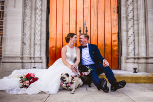 Bride and Groom Outdoor Portraits with Pet Dogs of Honor in St. Pete Florida | Wedding Pugs Wearing Flower Crown Collars | White Embroidered Organza Ballgown Illusion Neck Bib Neckline Bridal Gown and Classic Navy Groom Suit | Tampa Wedding Dress Shop Truly Forever Bridal