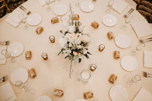 Monochromatic Neutral Wedding Reception Table with White Linens and Gold Votive Candles and White Floral Centerpiece of Ivory Roses Hydrangea Lillies and Orchids