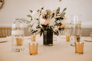 Monochromatic Neutral Wedding Reception Table with White Linens and Gold Votive Candles and White Floral Centerpiece of Ivory Roses Chrysanthemums Lillies and Orchids with accents of Blush Pink and Floating Candles