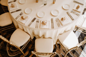 Monochromatic Neutral Wedding Reception Table with Gold Chiavari Chairs and White Linens and Gold Favor Boxes on White Napkins at Place Settings