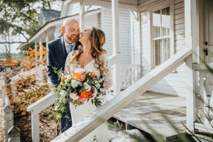 Ybor City Tampa Wedding Bride and Groom Outdoor Portrait | Long Sleeve Lace Bridal Gown Wedding Dress | Classic Navy Blue Groom Suit | Organic Natural Loose Wedding Bridal Bouquet with Coral Pink Peonies and White Roses with Succulents and Eucalyptus Greenery by Tampa Florida Monarch Events and Designs