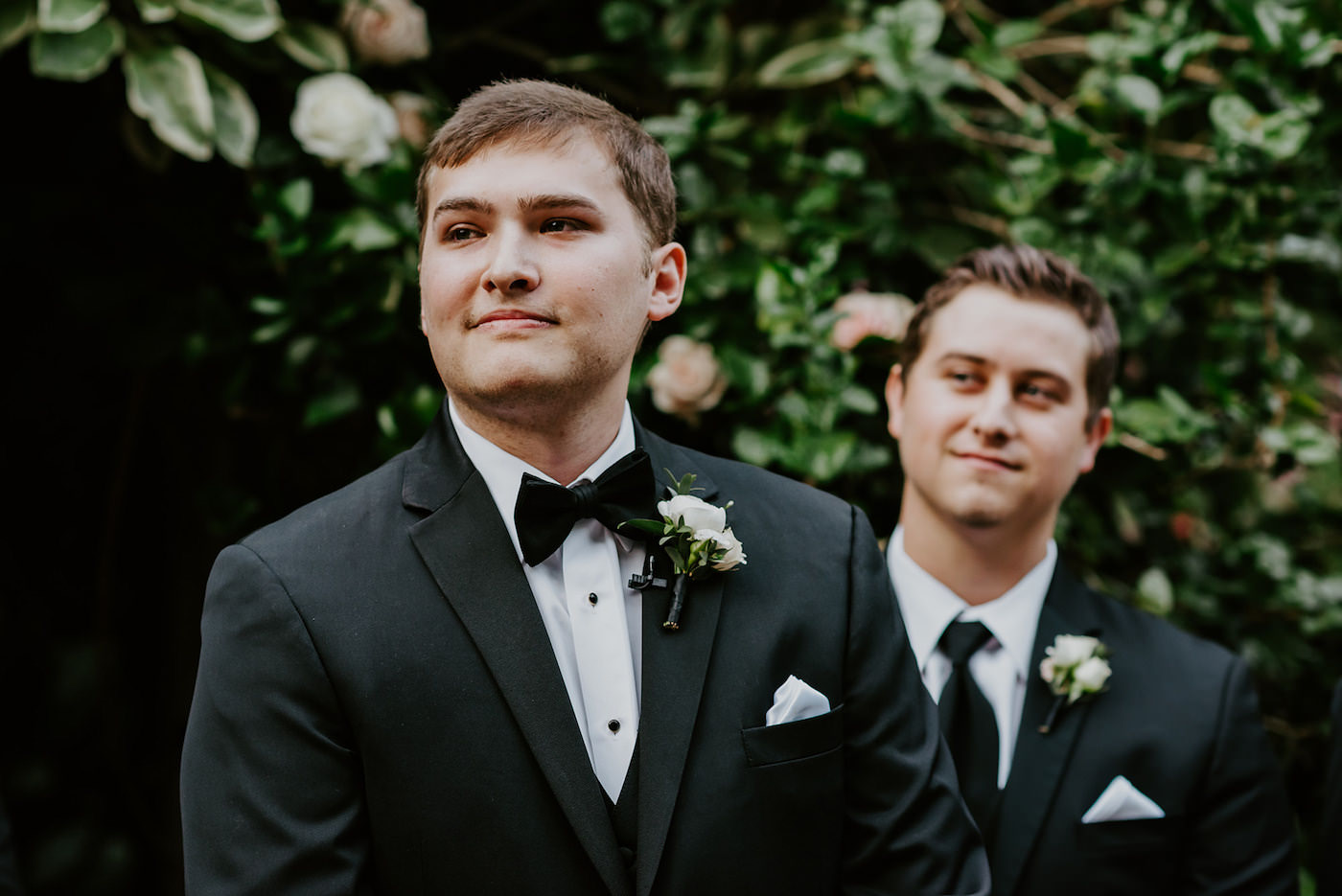 Groom in Classic Black Tuxedo Suit with Bow Tie and White Rose Boutonniere | Groom Seeing His Bride For The First Time During Wedding Ceremony