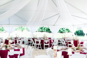 Outdoor Florida Wedding Reception Tent with Ceiling Draping and White Folding Garden Chairs | Burgundy Deep Red Bordeaux Table Linens with Gold Charger Plates and Gold Candlestick Centerpieces