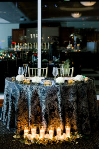 Formal New Year's Eve Wedding Reception Decor, Sweetheart Table with Black and Gold Tablecloth, Romantic Candles and Greenery, Gold Chiavari Chairs | Wedding Photographer Shauna and Jordon Photography | Tampa Bay Wedding Planner UNIQUE Weddings + Events, Wedding Rentals A Chair Affair
