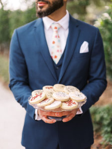 Spring Wedding Groom Wearing a Navy Blue Suit holding Pressed Flower Sugar Cookies