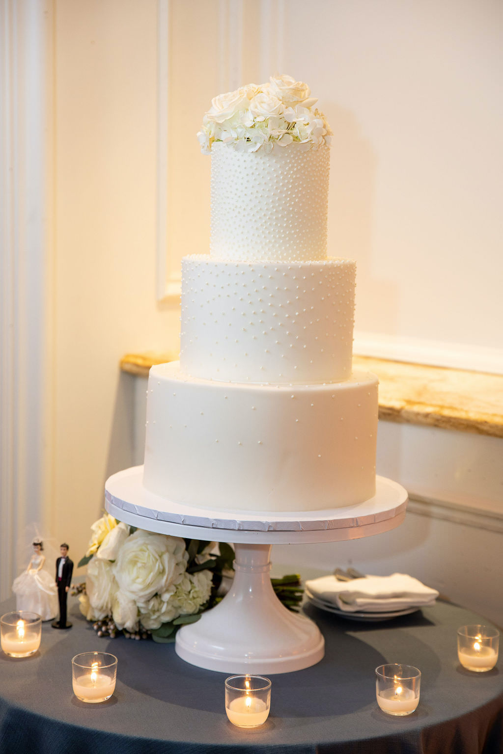 Classic Three Tier Buttercream Wedding Cake with Pearl Beaded Accents, White and Ivory Floral Topper, Tea Lights and Simplistic Cake Table Decor | Luxury Tampa Bay Wedding Planner NK Productions Wedding Planning