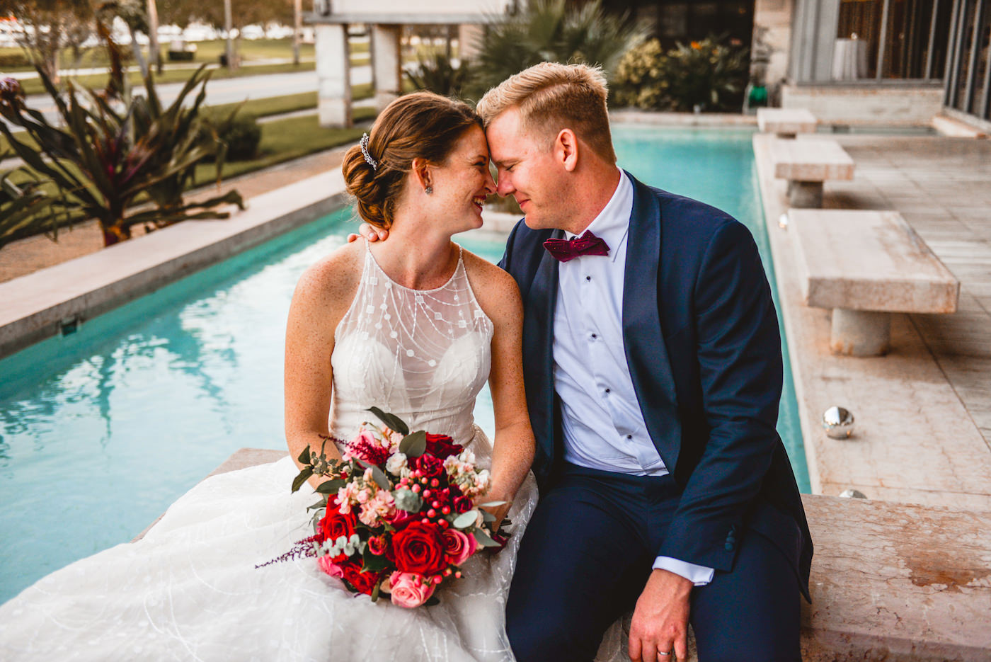 Bride and Groom Outdoor Waterfront Portrait at St. Pete Wedding Venue The Poynter Institute | White Embroidered Organza Ballgown Illusion Neck Bib Neckline Bridal Gown | Groom Classic Navy Blue Suit | Tampa Wedding Dress Shop Truly Forever Bridal