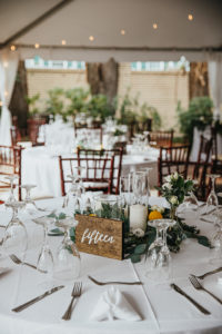 Round White Wedding Reception Tables with Mahogany Wood Chiavari Chairs and Wood Calligraphy Table Numbers | Eucalyptus Greenery Wreath Centerpieces with Lemons and Hurricane Pillar Candles by Tampa Wedding Florist Monarch Events and Designs