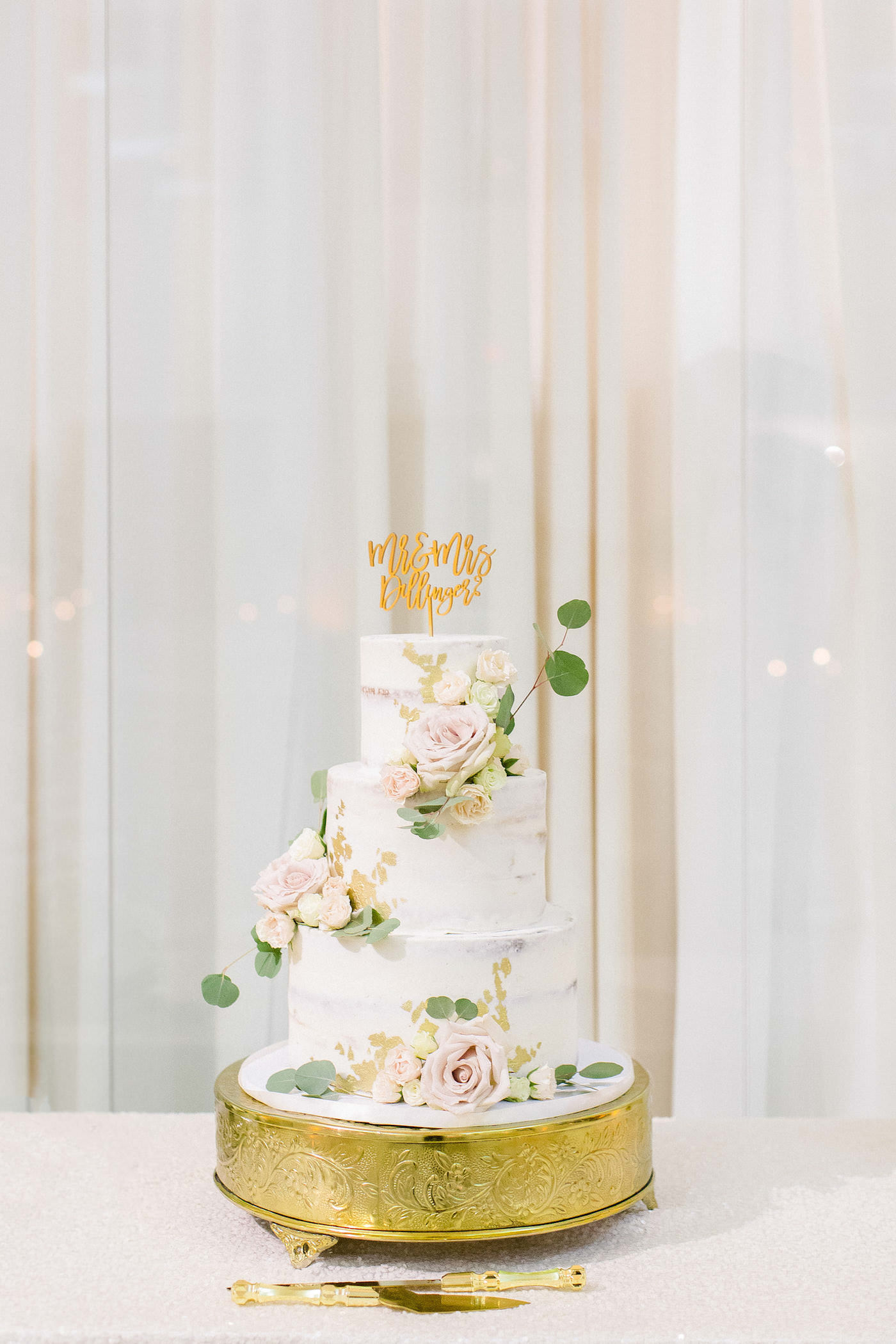 Classic Three Tier White Wedding Cake, Semi Naked Frosted Cake with Gold Foil Detailing, Blush Pink Roses Florals with Greenery Eucalyptus, Custom Gold Cake Topper and Serving Set | Tampa Bay Wedding Planner Breezin' Weddings