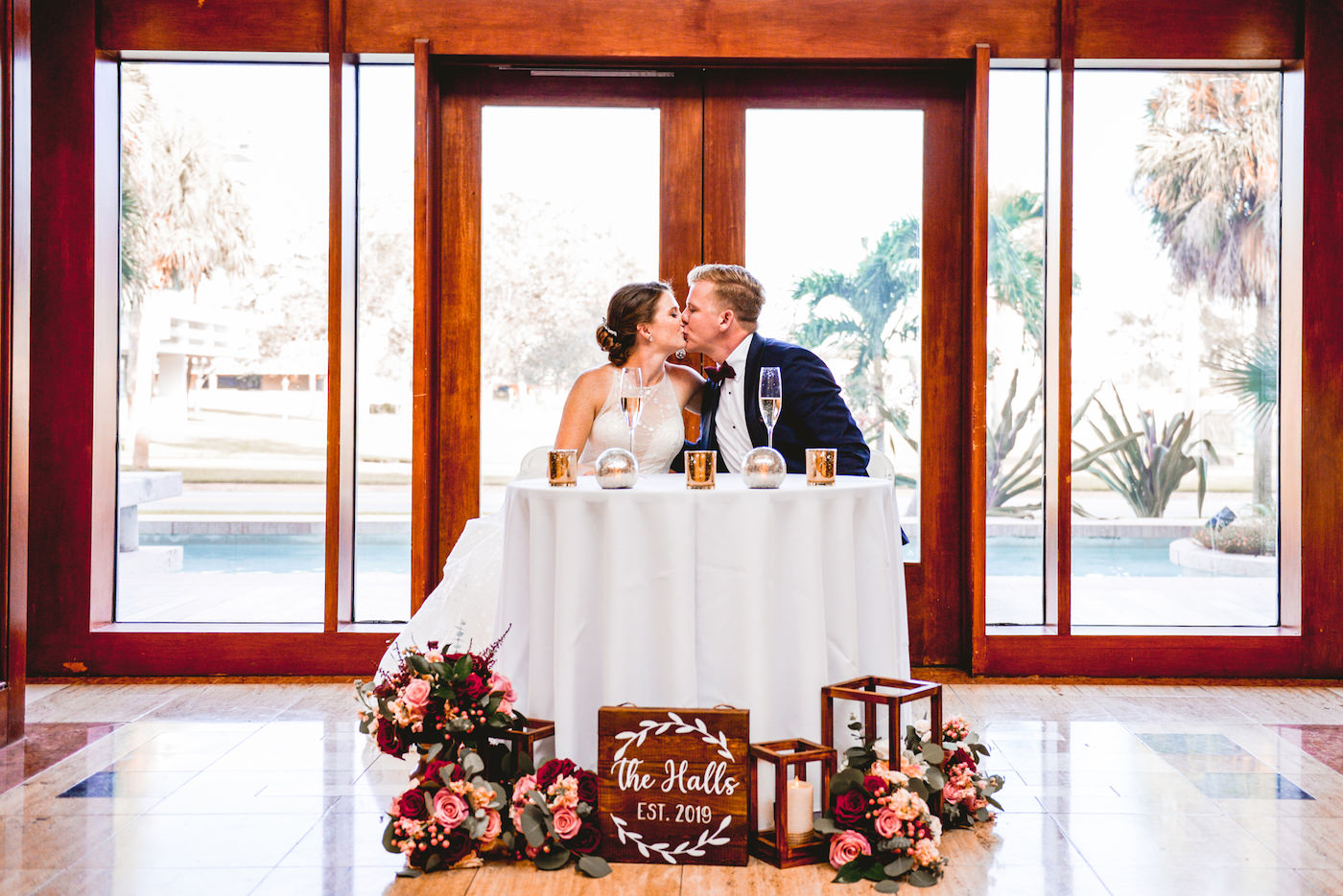 St. Pete Wedding Venue The Poynter Institute | Bride and Groom Sweetheart Table with Wood Lanterns and Candles and Blush Pink and Red Bouquets