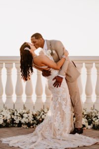 Bride and Groom First Kiss at Clearwater Wedding Venue Hyatt Regency Clearwater Beach Hotel | Outdoor Rooftop Waterfront Wedding Portrait | Champagne Lace Sheath Illusion Neck Bridal Gown with Criss Cross Back Straps | Groom Khaki Tan Suit