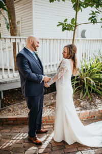 Ybor City Tampa Wedding Bride and Groom Outdoor First Look | Long Sleeve Lace Bridal Gown Wedding Dress | Classic Navy Blue Groom Suit