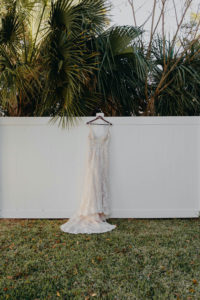 Tampa Wedding Dress Outdoor Hanger Shot on White Fence | Mori Lee Ivory Lace over Champagne Lining Spaghetti Strap V Neck Mermaid Bridal Gown
