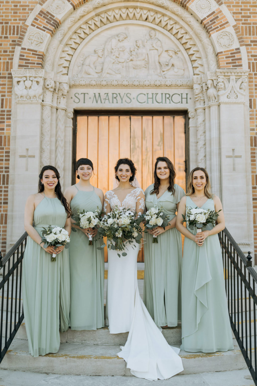 Classic Tampa Bay Bride and Bridesmaids, Bride Wearing Illusion Lace Long Sleeve Martina Liana Wedding Dress, Bridesmaids in Long Mix and Match Sage Green Azazie Dresses, Holding Elegant White Anemone Floral Bouquet with Greenery, The Steps of Saint Mary Our Lady of Grace Catholic Church in St. Petersburg | Florida Wedding Planner Blue Skies Weddings and Events | St. Pete Beach Hair and Makeup Artist Femme Akoi Beauty Studio