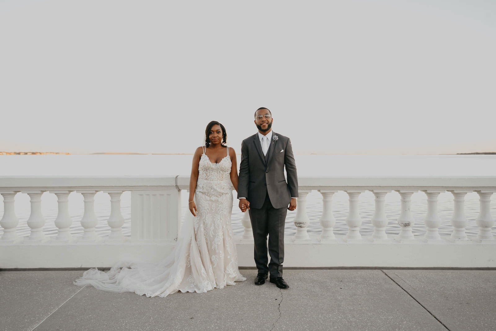 Bride and Groom Outdoor Portrait on Bayshore | Groom in Classic Charcoal Grey Suit | Mori Lee Ivory Lace over Champagne Lining Spaghetti Strap V Neck Mermaid Bridal Gown with Long Cathedral Veil