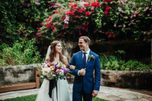 Bride Holding Colorful Boho Wildflower Bouquet and Groom in Blue Suit Wedding Portrait at St. Petersburg Wedding Venue Sunken Gardens | Tampa Wedding Planner Kelly Kennedy Weddings and Events