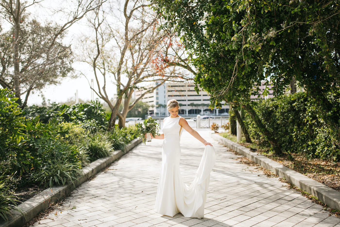 Outdoor Tampa Waterfront Bridal Portrait | Simple Sheath Ivory Crepe Bateau Neck Bridal Gown by Theia | Natural Loose Greenery Bridal Bouquet with Eucalyptus and Succulents and White Roses | Winsor Event Studio