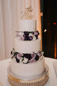 Three Tier Publix Wedding Cake with Textured Buttercream Icing and Purple and White Roses with Die Cut Gold Mr and Mrs Cake Topper on Gold Crystal Beaded Cake Stand