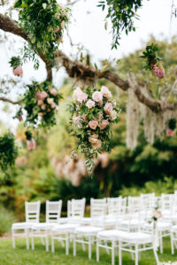 Romantic, Garden Inspired Wedding Ceremony, Large Floral Decor Hanging From Tree Branches Outside, Blush Pink Roses and Peonies, with Greenery, White Chiavari Chairs | Florida Wedding Planner NK Weddings | Marie Selby Botanical Gardens