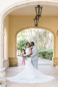 Florida Bride and Groom Wedding Portrait Outside Historic Powel Crosley Estate in Sarasota, Bride Holding Romantic Bridal Bouquet with Blush Pink King Protea, Red Roses, Burgundy Bow, | Tampa Bay Wedding Photographer Kera Photography