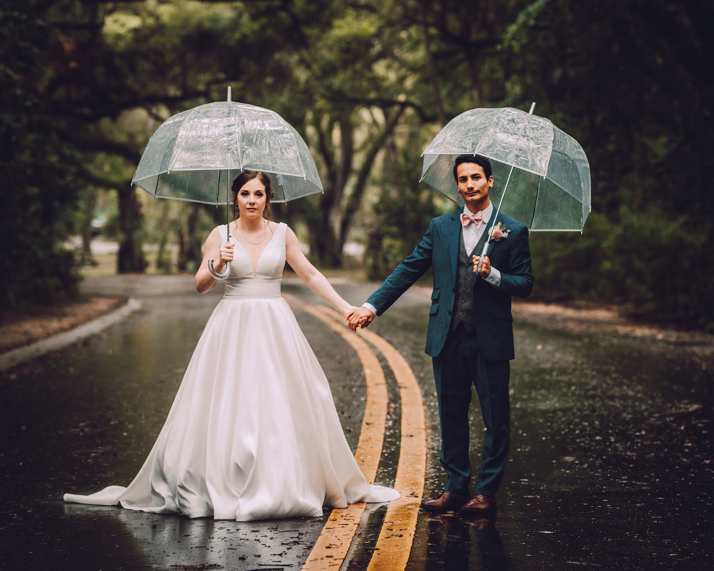 Bride and Groom Rainy Wedding Day Portrait with Clear Umbrellas | Stella York Satin V Neck Simple Classic Low Back Bridal Gown A Line Ballgown | Navy Blue Suit Groom Suit with Grey Vest and Blush Pink Bow Tie