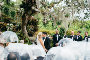 Romantic Florida Wedding Outside in Garden Inspired Ceremony Under Large Tree with Hanging Moss, Guests with Clear Umbrellas In the Rain | Sarasota Wedding Planner NK Weddings