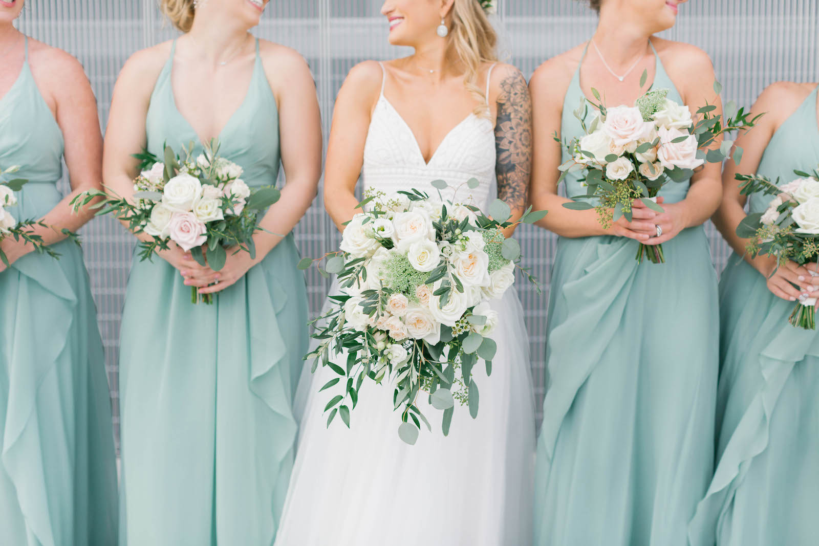 Boho Chic Bride in A-Line V Neckline Spaghetti Strap Wedding Dress with Tulle Skirt, Bridesmaids in Matching Sage Green Dresses Holding Ivory Roses and Greenery Floral Bouquets | Tampa Bay Wedding Florist Bruce Wayne Florals