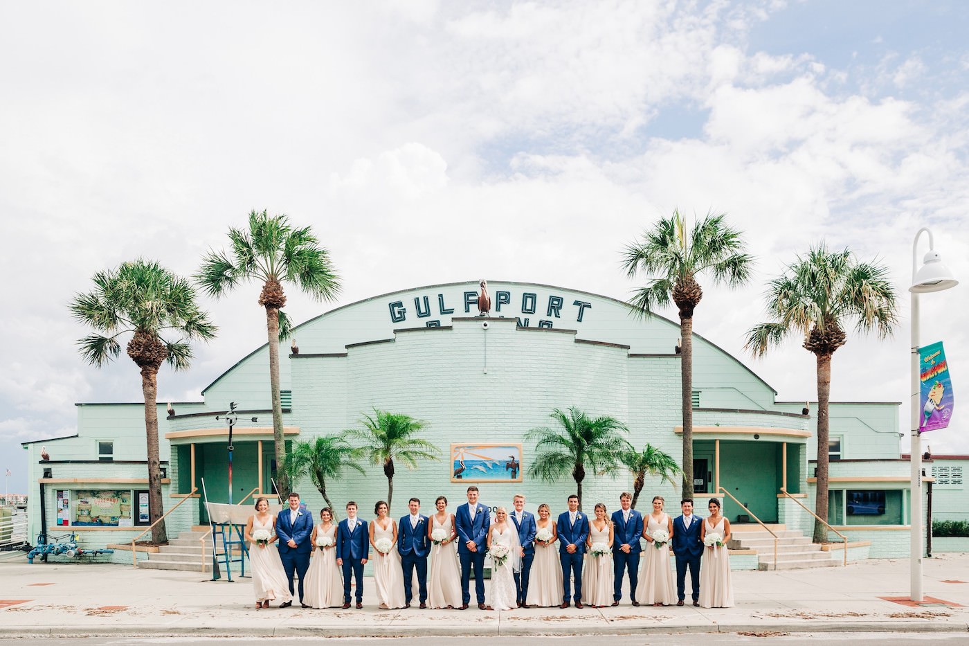 St. Petersburg Florida Wedding | Outdoor Wedding Party Portrait | Neutral Nude Champagne Watters Bridesmaid Dresses from Bella Bridesmaid | White Hydrangea Bouquets with Cascading Ribbon | Groom and Groomsmen in Navy Blue Suits with Nude Pink Neck Ties | Gulfport Casino Wedding