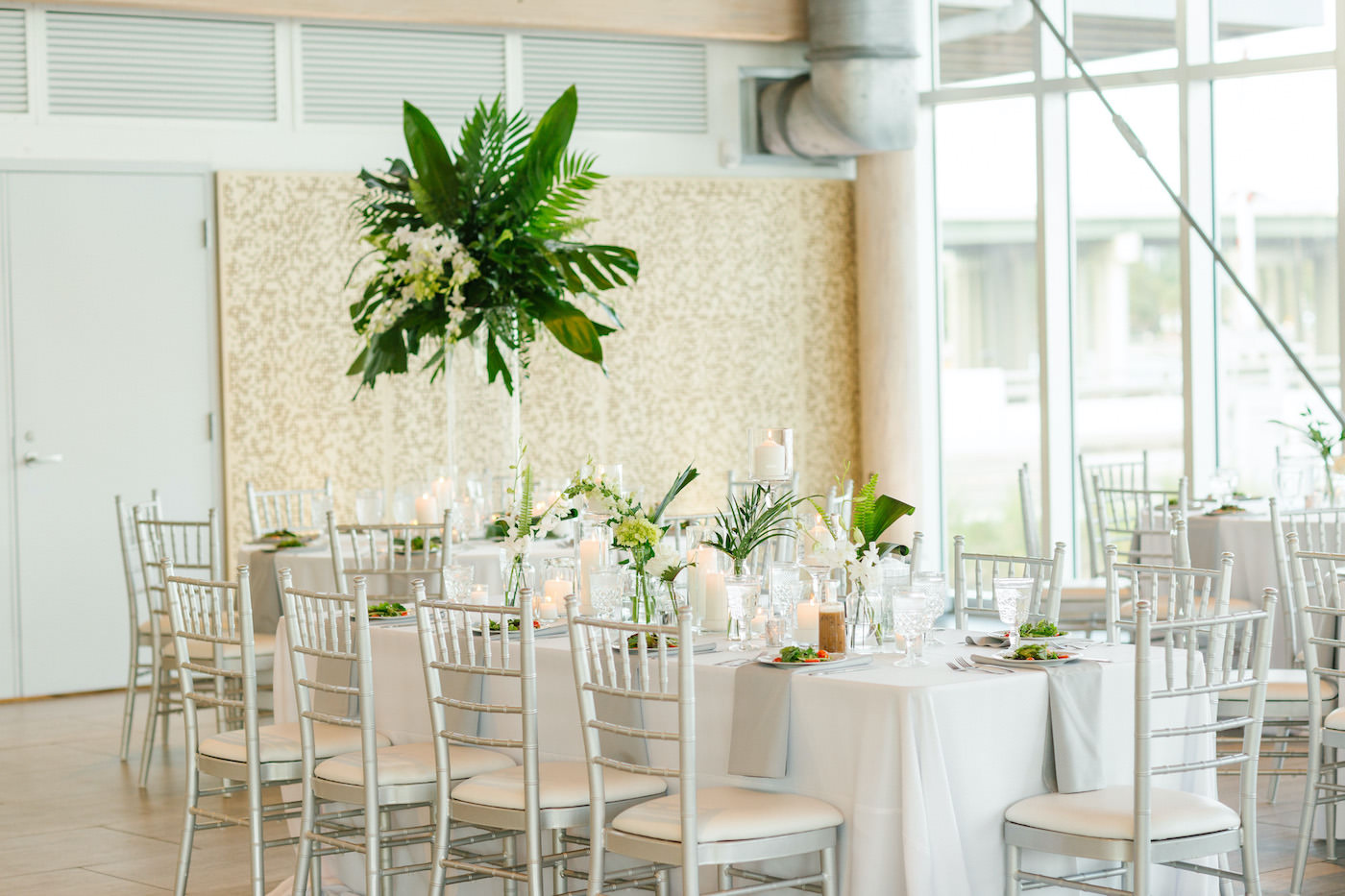 Tropical Tampa Florida Wedding Reception | White Wedding Banquet Feasting Table with Silver Chiavari Chairs and Grey Napkins and Tropical Palm Leaf Centerpiece with White Orchids | Tampa Wedding Florist Bruce Wayne Florals