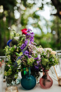 Boho Vintage Wildflower Wedding Reception Centerpiece, Purple and Red Florals with Greenery and Antique Blue and Pink Vases