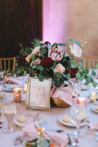 Romantic Wedding Decor at Reception, Low Floral Centerpiece with Gold Vase, Dark Red Burgundy Roses, Light Pink King Protea, Ivory Flowers, on White Linen Round Table with Gold Chiavari Chairs and Blush Cloth Linens and Gold Napkin Rings and Antique Silver Picture Fram Table Number | Tampa Bay Wedding Photographer Kera Photography | Florida Wedding Planner Special Moments Event Planning | Tampa Bay Wedding Rental Gabro Event Services