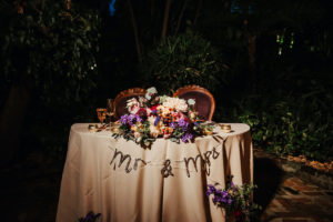 Whimsical Vintage Boho Sweetheart Table Wedding Reception Decor, Ivory Linen, Mr and Mrs Sign, Purple, Pink, Blush Dahlia, Red Berries, Roses and Greenery Floral Arrangement, Antique Chairs | Tampa Bay Wedding Planner Kelly Kennedy Weddings and Events