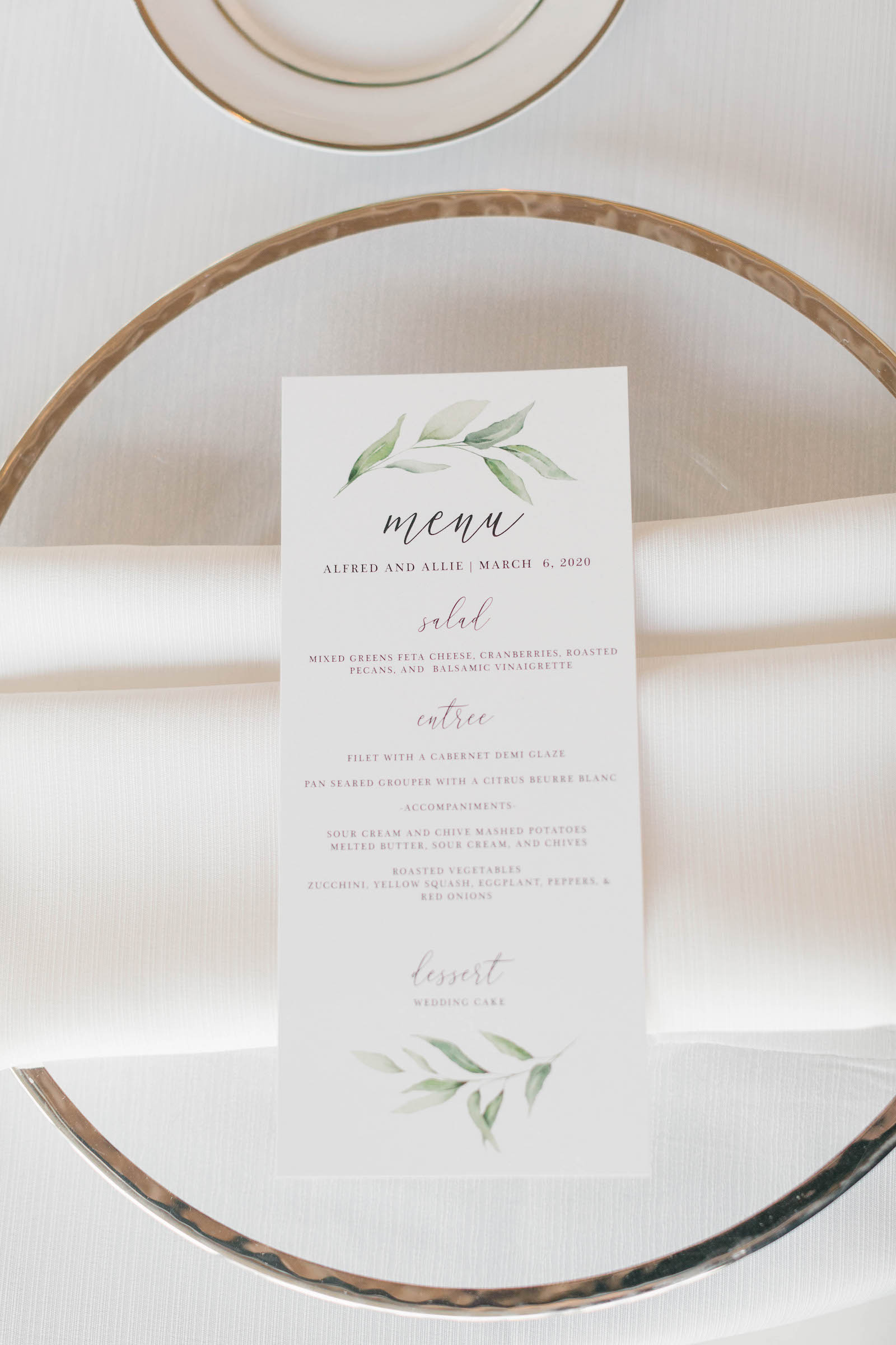 Elegant Gold Rimmed and Clear Chargers, Custom Menu with Watercolor Greenery Leaf and White Linen Napkin | Wedding Chargers Rentals Gabro Event Services | Catering by the Family